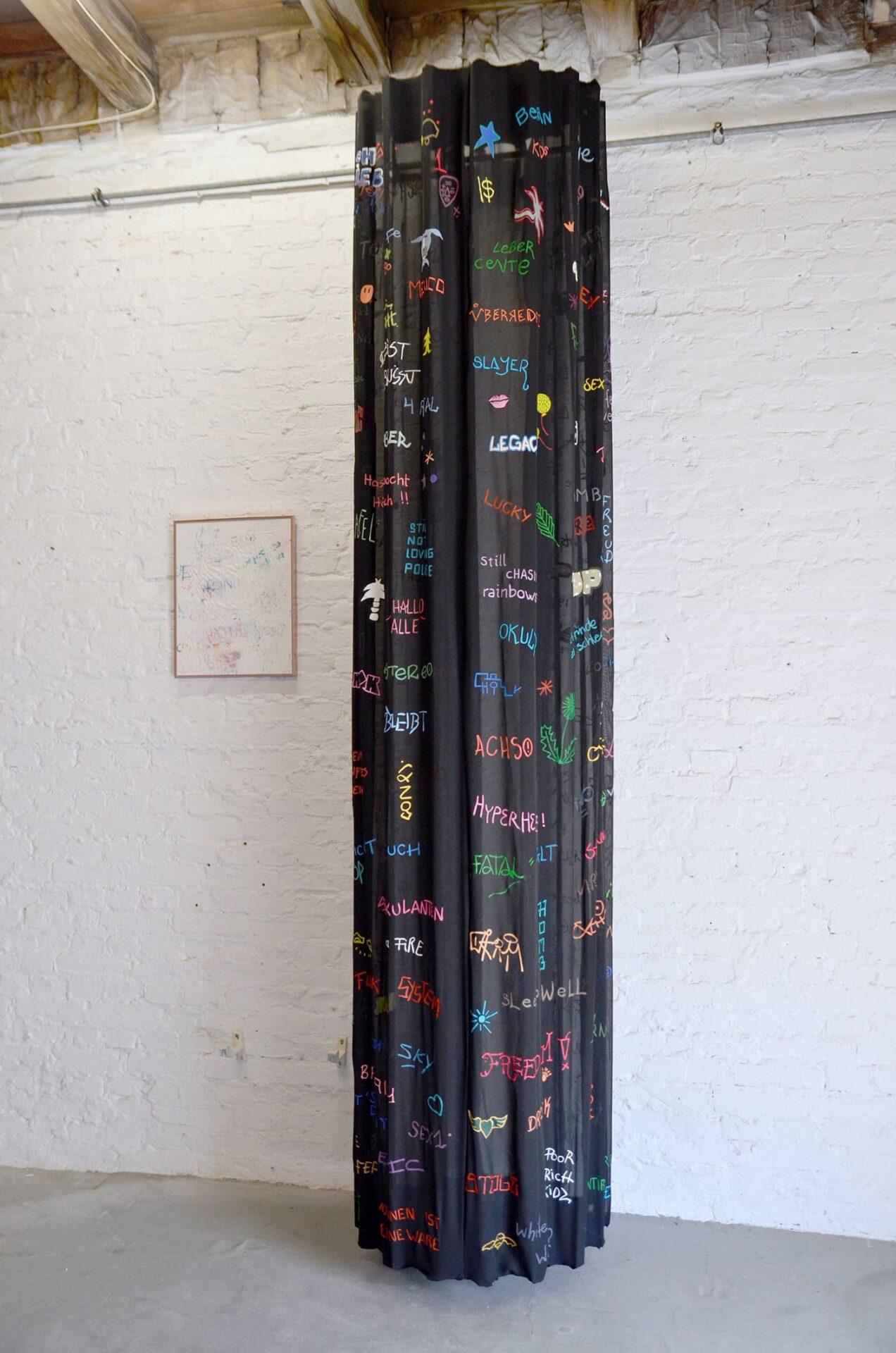 Painting of colored written words fragments on a black surface creating a column, by artist Patricia Sandonis