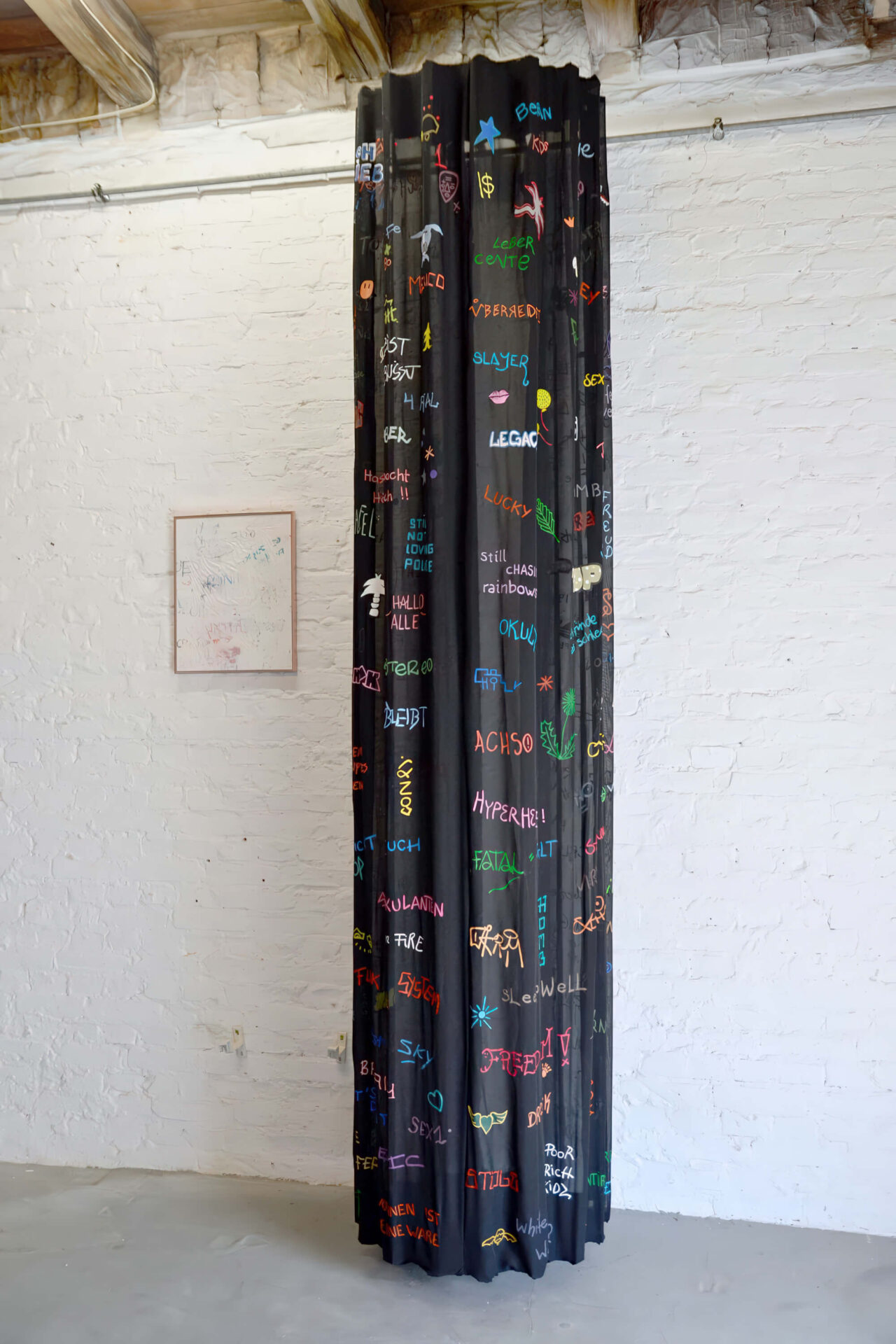 Painting of colored written words fragments on a black surface creating a column, by artist Patricia Sandonis