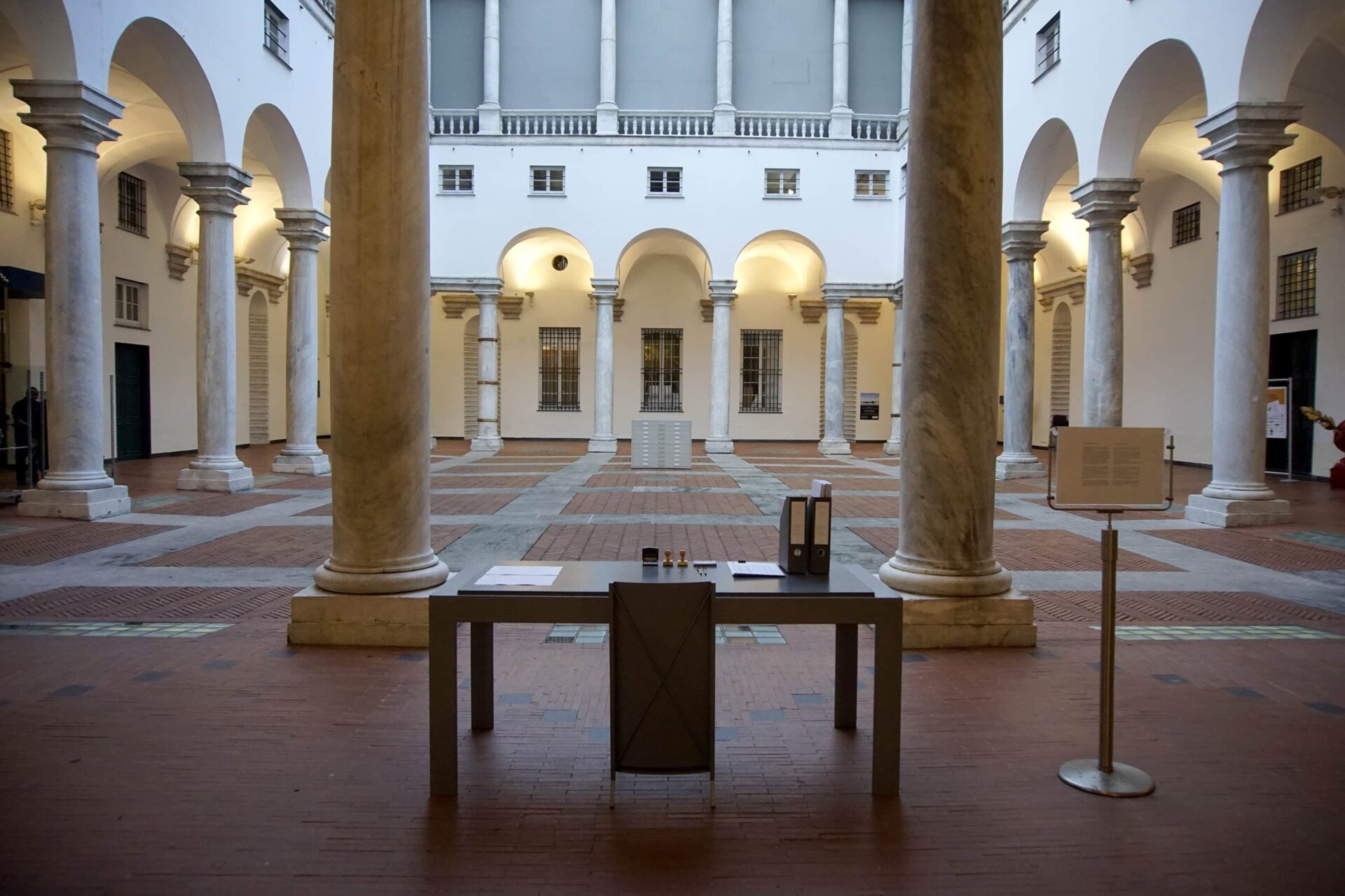 Patricia Sandonis artistic installation at Palazzo Ducale, showing a desk, a chair and folders in the courtyard