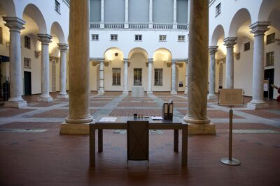 Patricia Sandonis artistic installation at Palazzo Ducale, showing a desk, a chair and folders in the courtyard