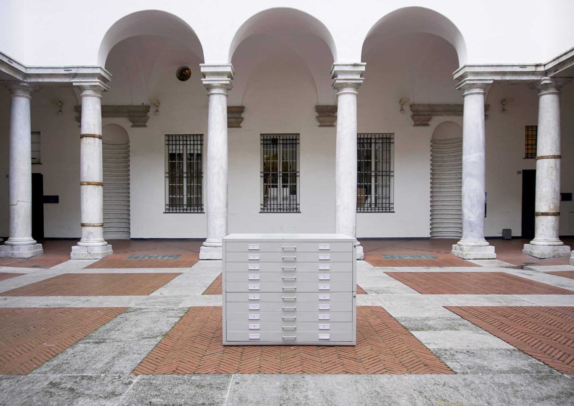 Art Installation by artist Patricia Sandonis showing a gray cupboard cabinet in the middle of an inner courtyard