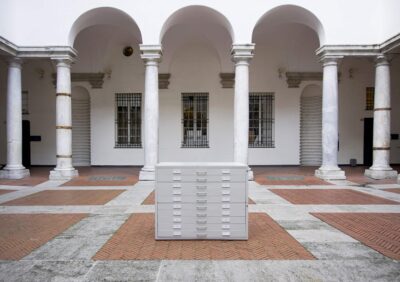 Art Installation by artist Patricia Sandonis showing a gray cupboard cabinet in the middle of an inner courtyard