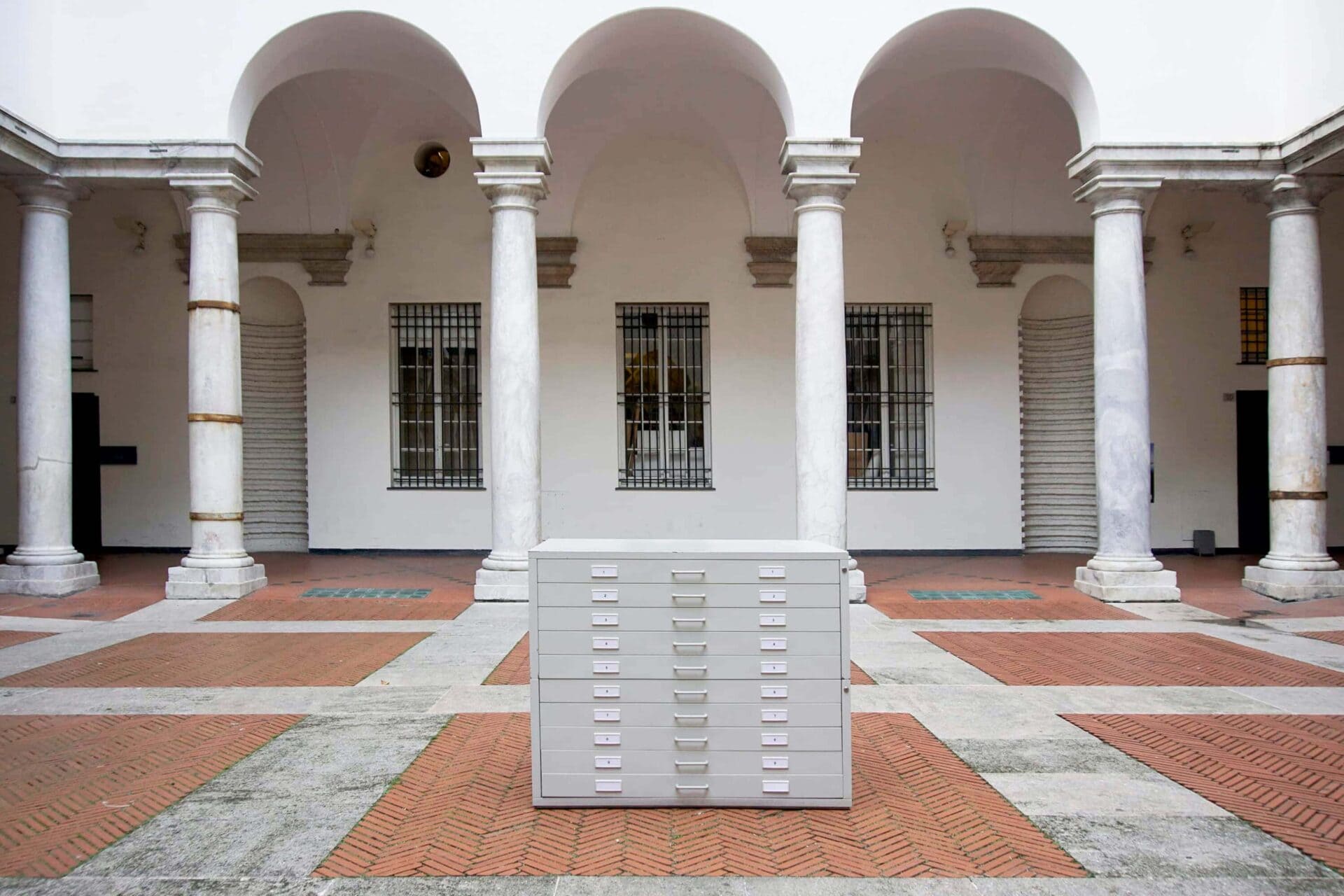 Art Installation by artist Patricia Sandonis showing a gray cupboard cabinet in the middle of an inner courtyard