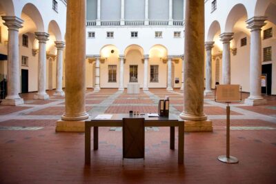 Patricia Sandonis artistic installation at Palazzo Ducale, showing a desk, a chair and folders in the courtyard