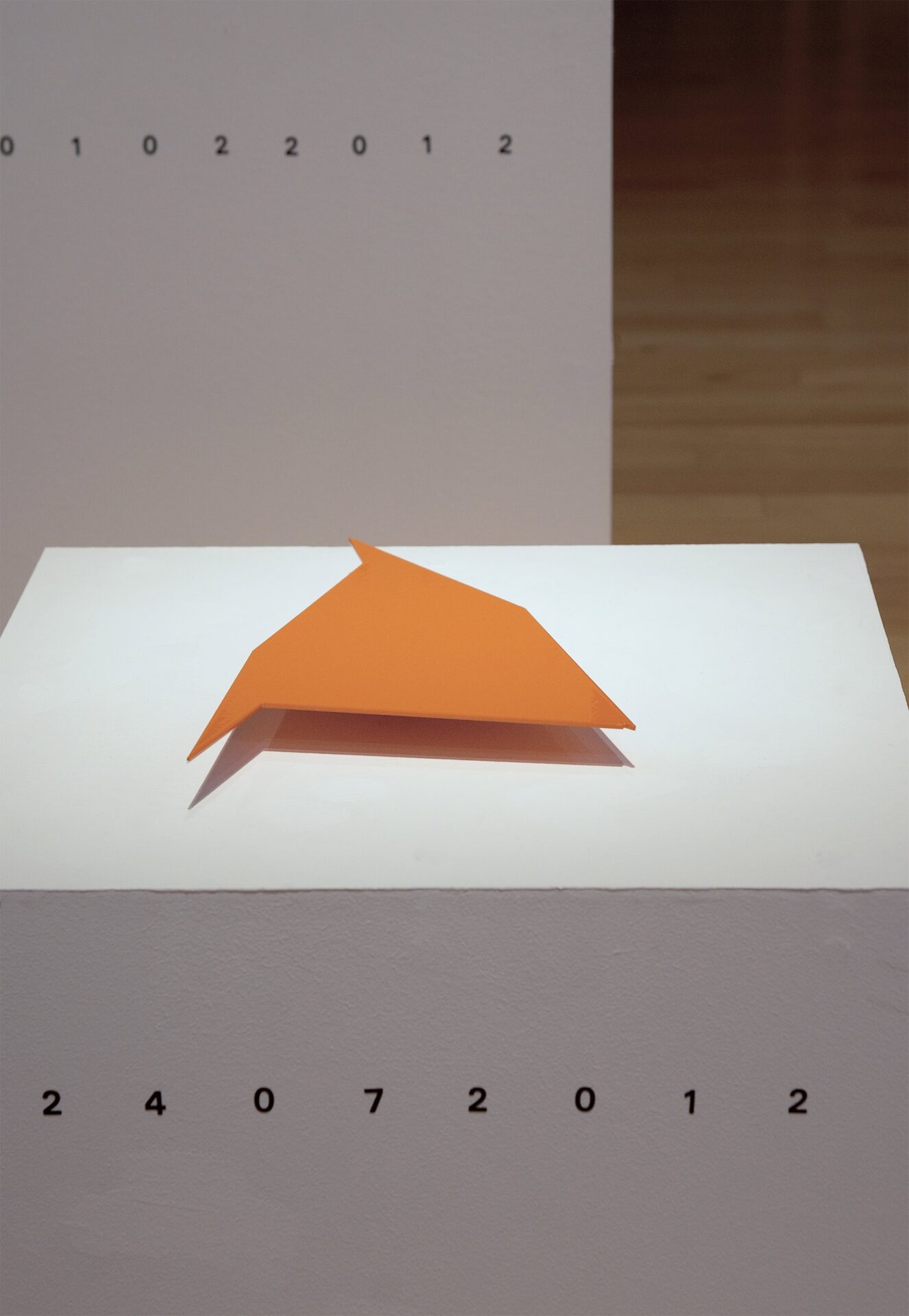 Patricia Sandonis, art installation with an orange geometrical stainless steel shape on a white pedestal
