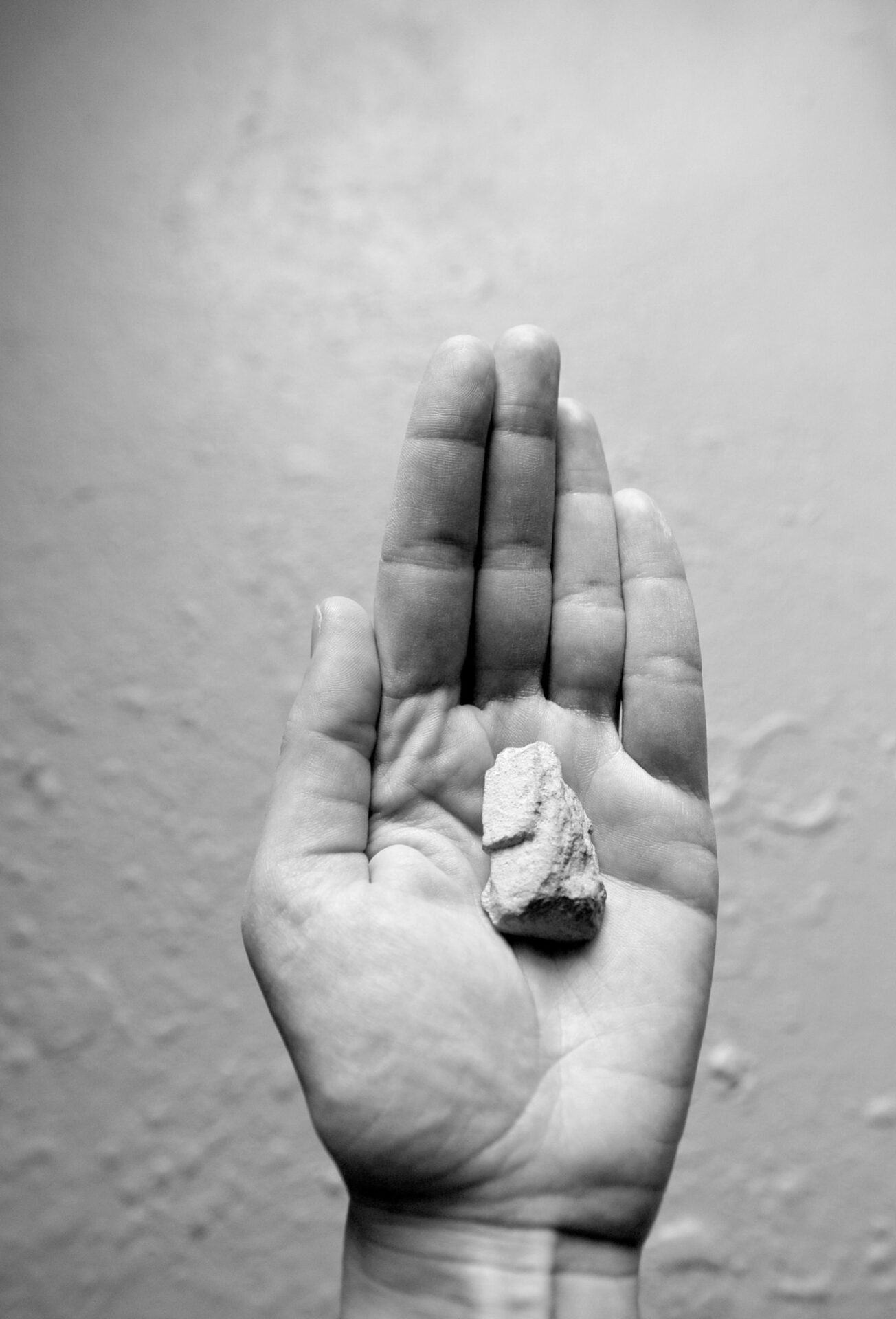 Black and white photography showing a left hand with a small stone
