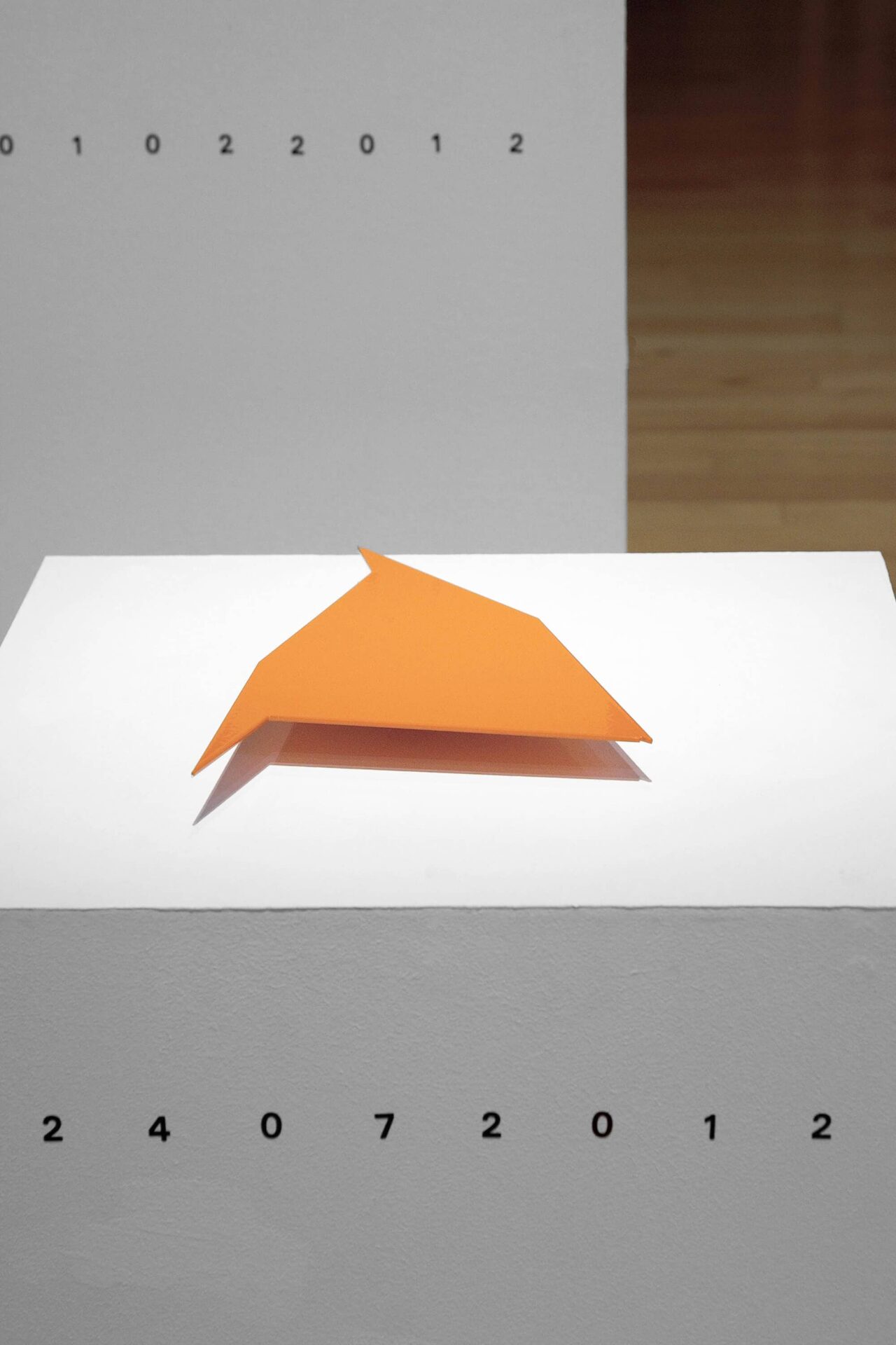 Patricia Sandonis, art installation with an orange geometrical stainless steel shape on a white pedestal