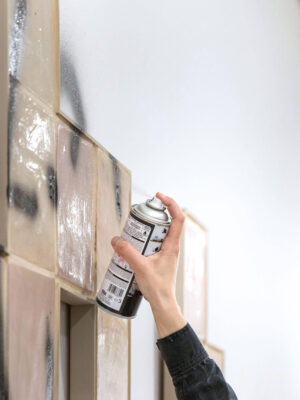 Detail from the performance of Patricia Sandonis where the artist writes a graffiti message on the ceramic art installation at Museo Patio Herreriano in Valladolid