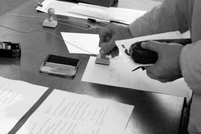 Black and white photography showing a person stamping a seal on paper