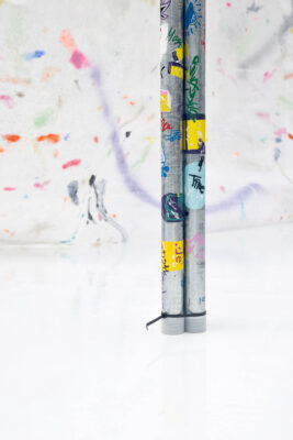 Colorful self-made stickers on metal tubes on a white floor, an art installation by artist Patricia Sandonis