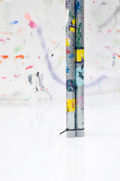Colorful self-made stickers on metal tubes on a white floor, an art installation by artist Patricia Sandonis