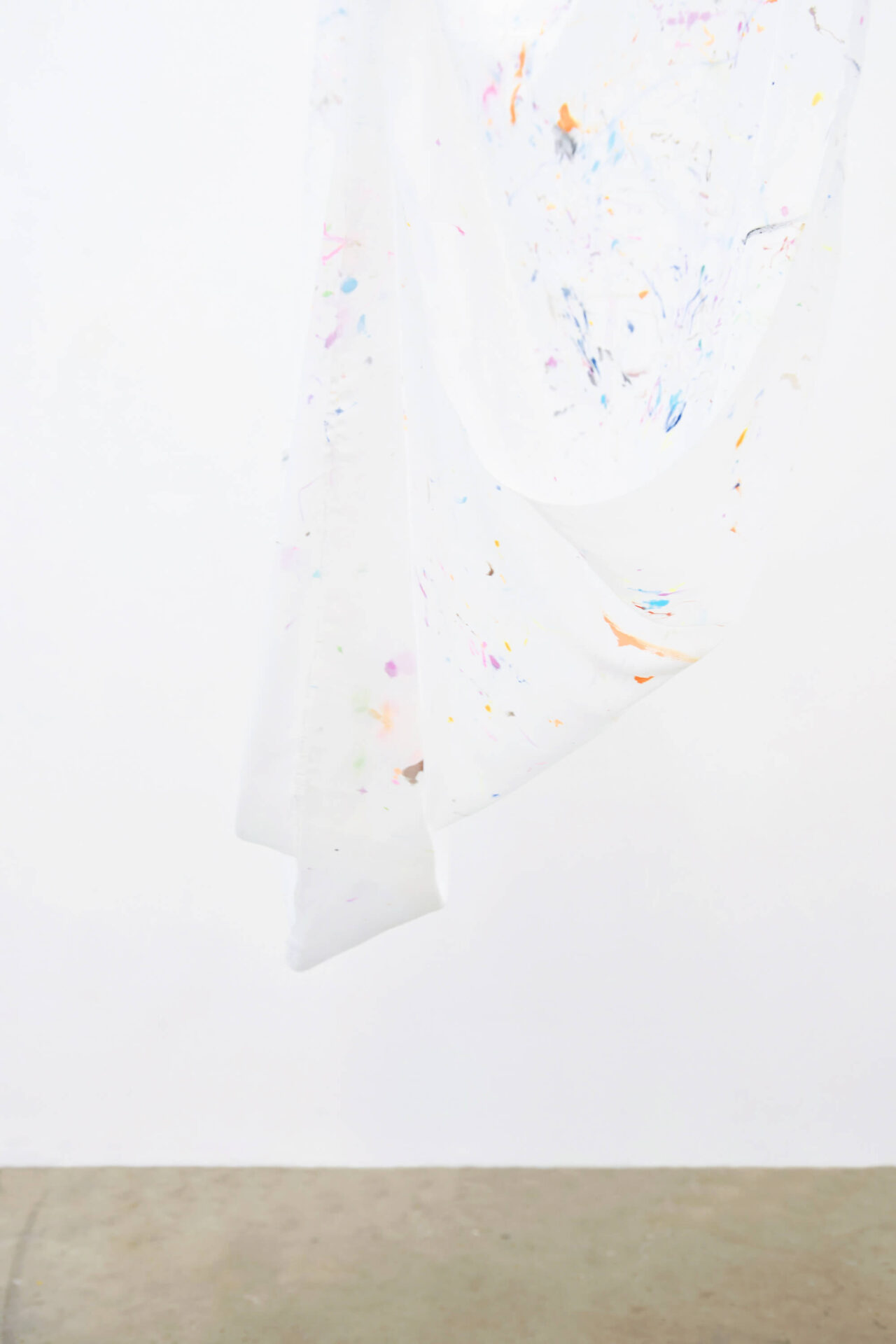 White fabric with small color fragments hanging. Art installation by Patricia Sandonis at gallery ángels Barcelona