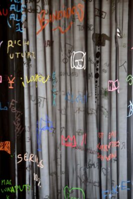 Different colored sentences written and painted on a semi-transparent black chiffon fabric, detail of an artwork by Patricia Sandonis