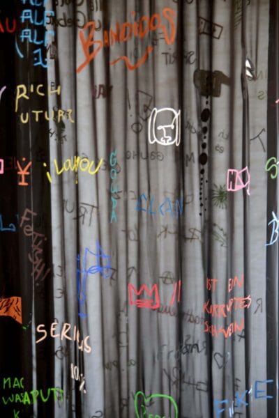 Different colored sentences written and painted on a semi-transparent black chiffon fabric, detail of an artwork by Patricia Sandonis