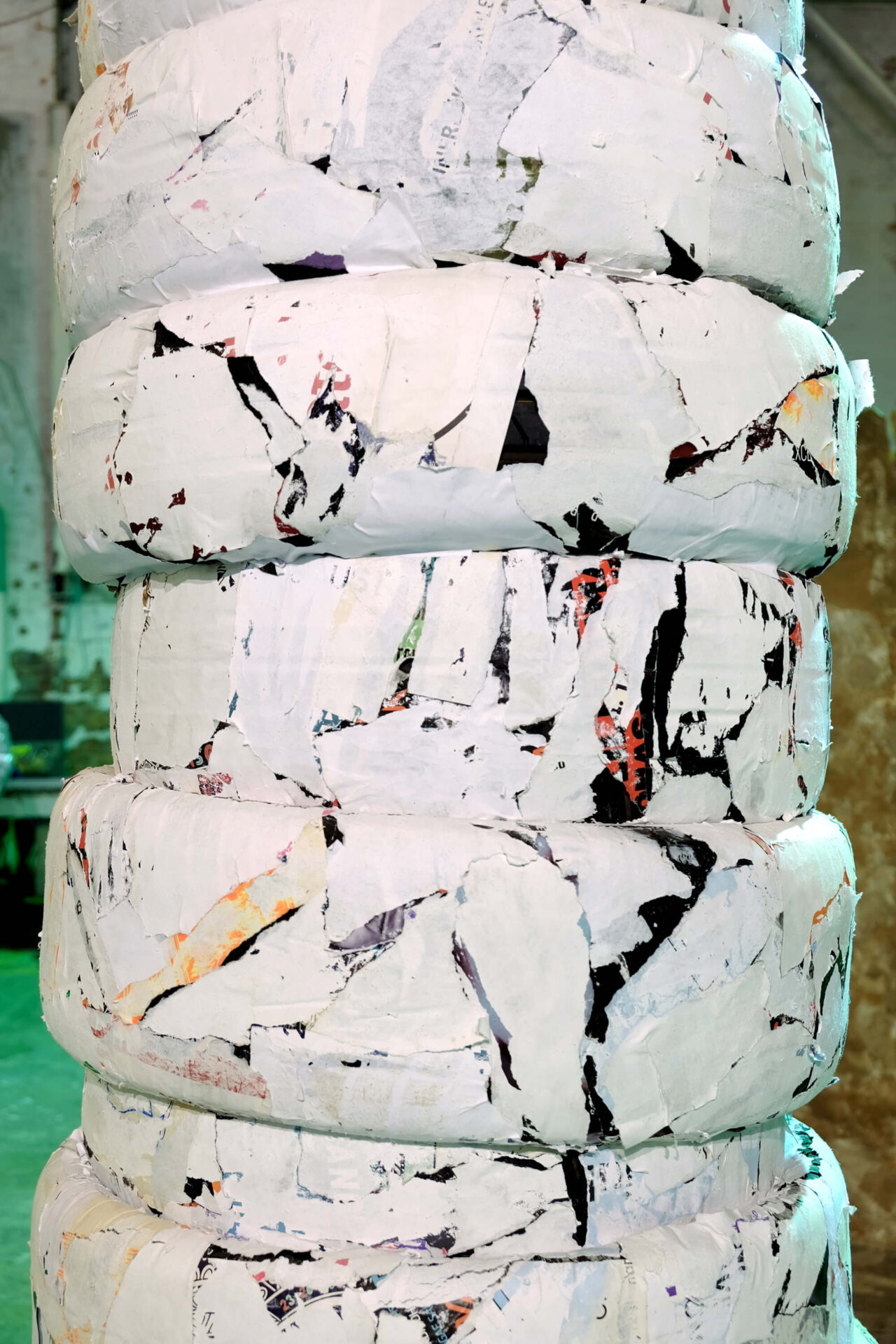 Patricia Sandonis art installation detail, showing fragments of black and white paper on car tires forming a column.