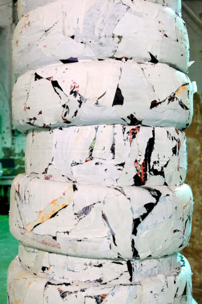 Patricia Sandonis art installation detail, showing fragments of black and white paper on car tires forming a column.