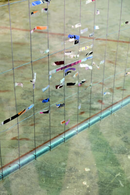 Detail of a construction fence with remnants of colorful fragments of posters on cellophane. An artwork by artist Patricia Sandonis