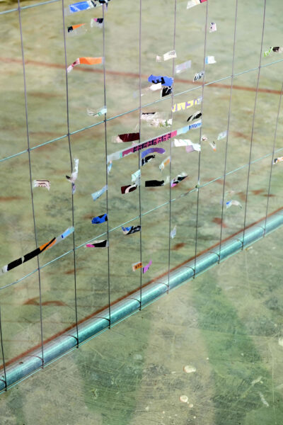 Detail of a construction fence with remnants of colorful fragments of posters on cellophane. An artwork by artist Patricia Sandonis