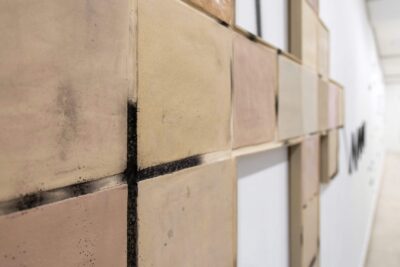 Detail from the ceramic art installation The In Between by Patricia Sandonis, showing the black color left after the writing performance