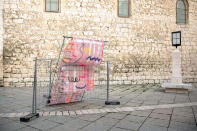 Pink painting and sculptural installation with fences in the public realm by artist Patricia Sandonis