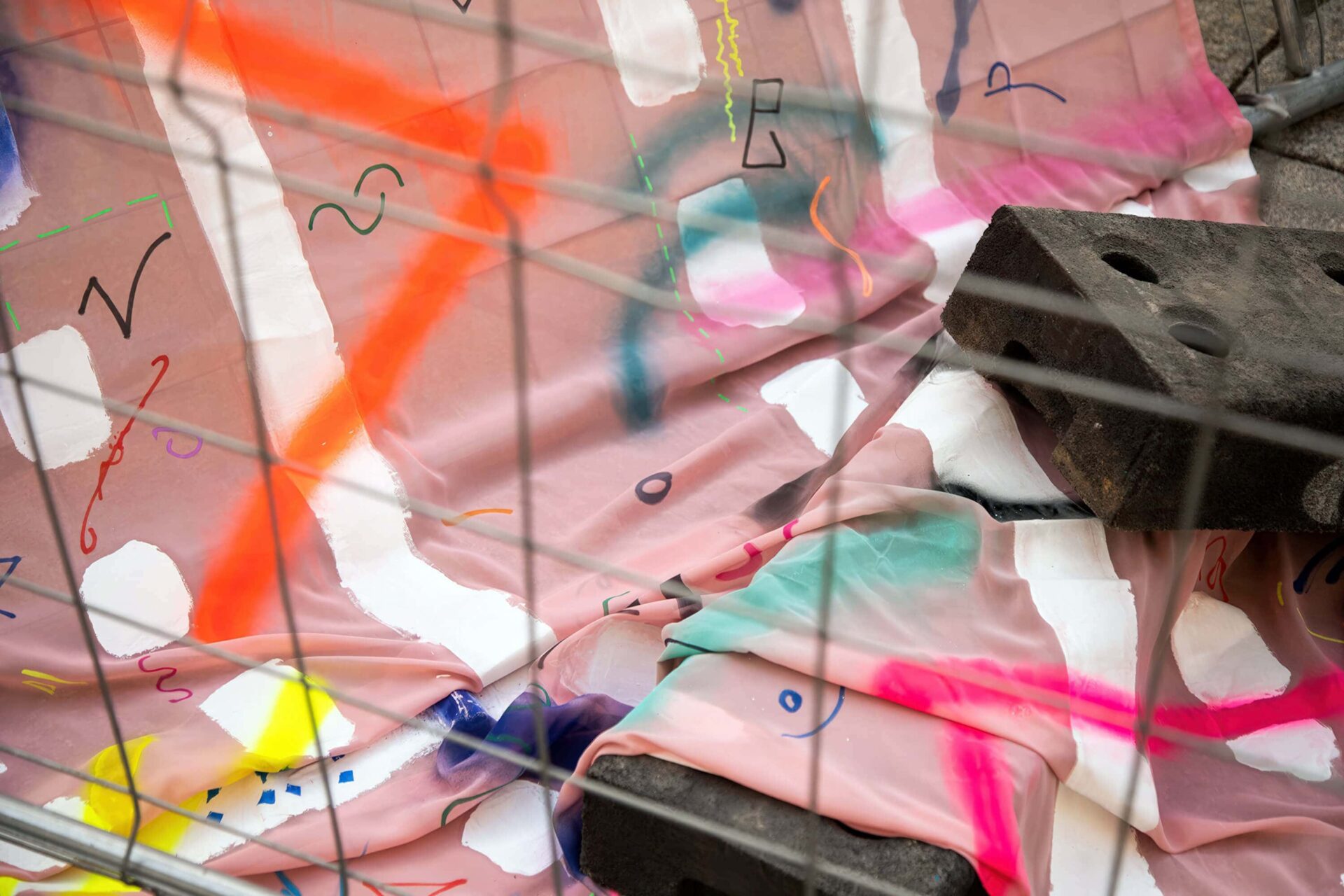 Detail from a pink painting and fence feet installation in the public realm by artist Patricia Sandonis