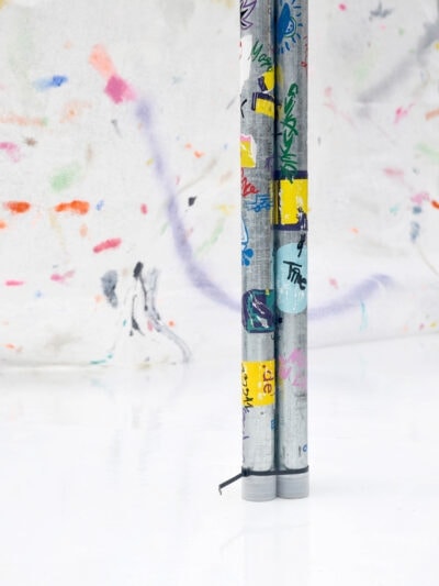 Colorful self-made stickers on metal tubes on a white floor, an art installation by artist Patricia Sandonis