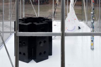 Group of black fence feet, placed vertically behind a glass window, an art installation by Patricia Sandonis