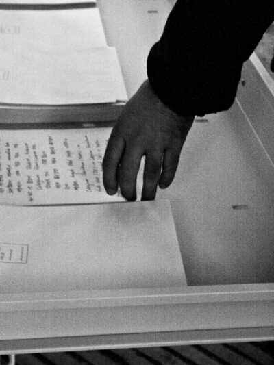 Black and white photography showing a hand picking up a written paper at the art installation titled Exchange Value Intercultural